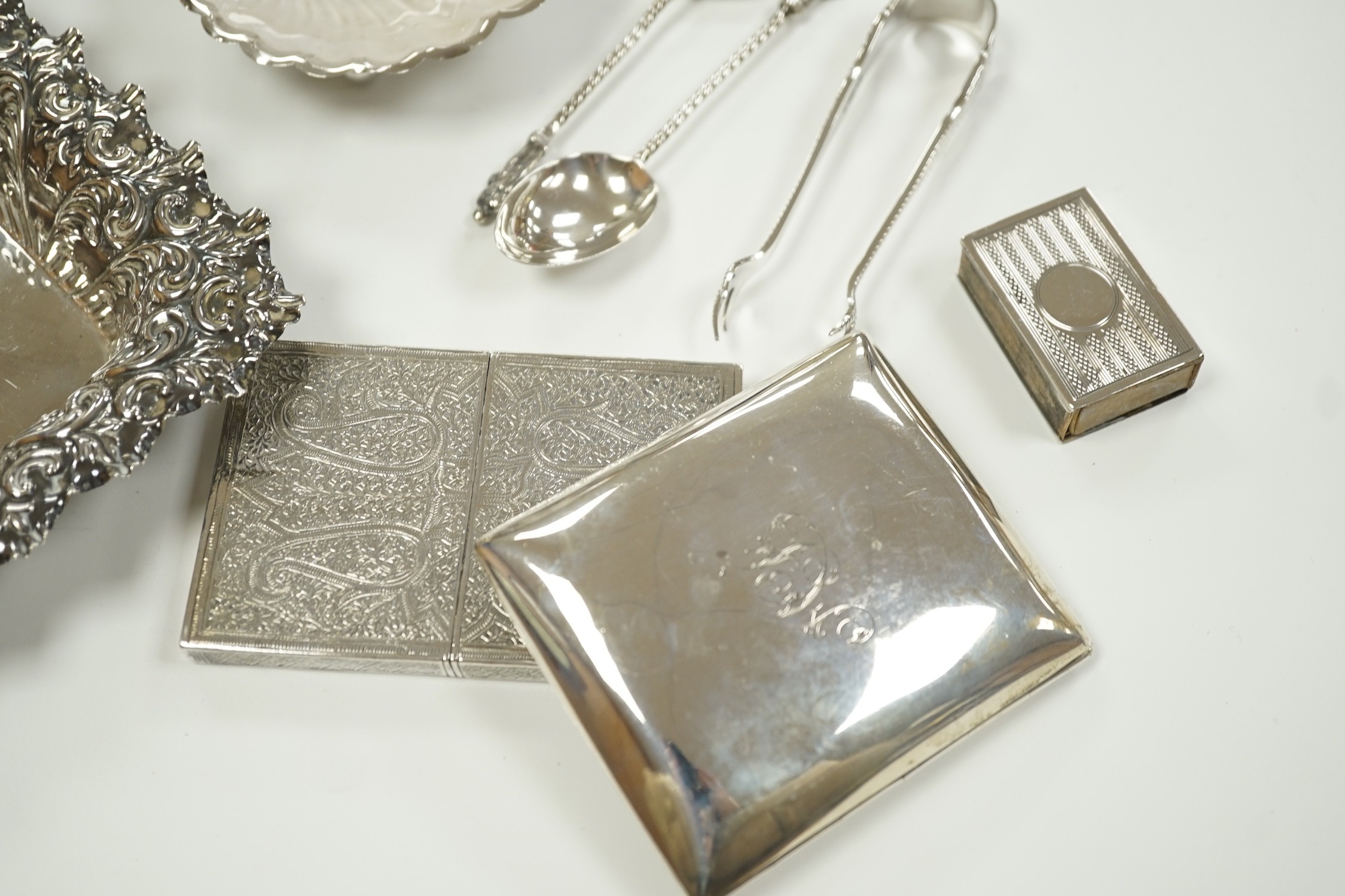 A small group of collectable silver including a repousse bonbon dish, 13.5cm, cigarette case, silver cream jug and sugar bowl, butter shell, vesta case, match sleeve, two apostle teaspoons and a George III curved silver